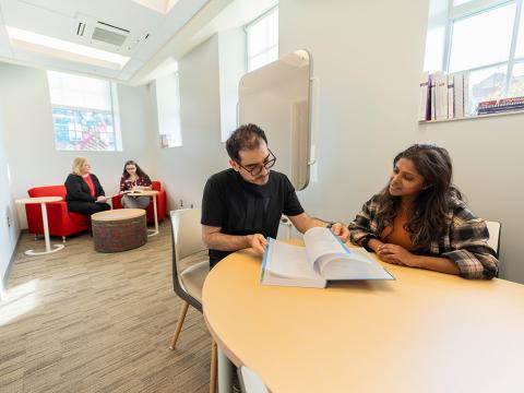 Man and young woman sitting at a table looking at a booklet
