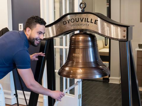 Man ringing a ceremonial D'Youville bell