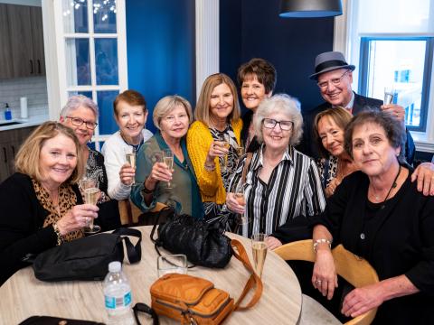 Alumni sitting around a table toasting