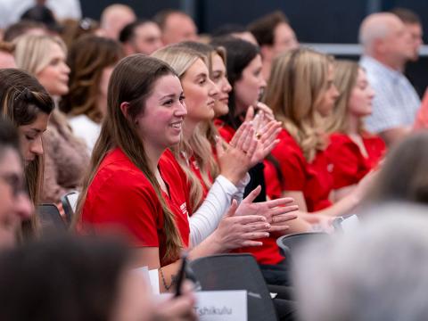 Students in nursing scrubs smiling at a presentation