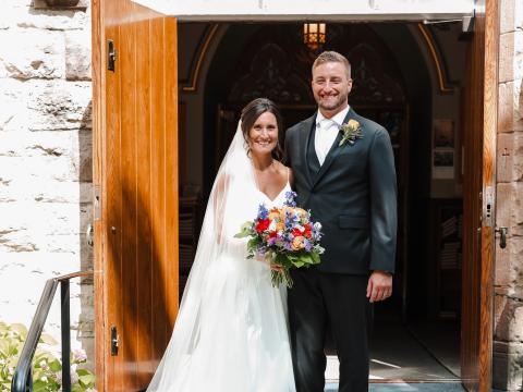 Bride and groom smiling in front of church doors