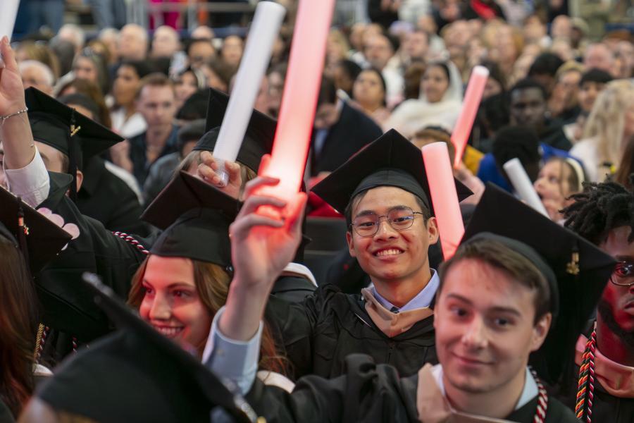Graduates waving light sticks at commencement ceremony