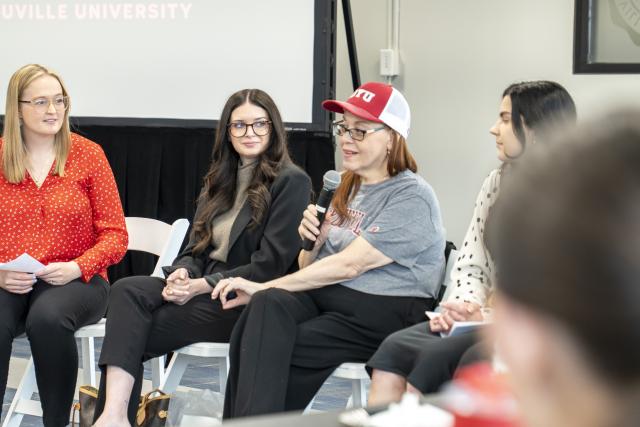 Woman speaking to younger women seated in a circle